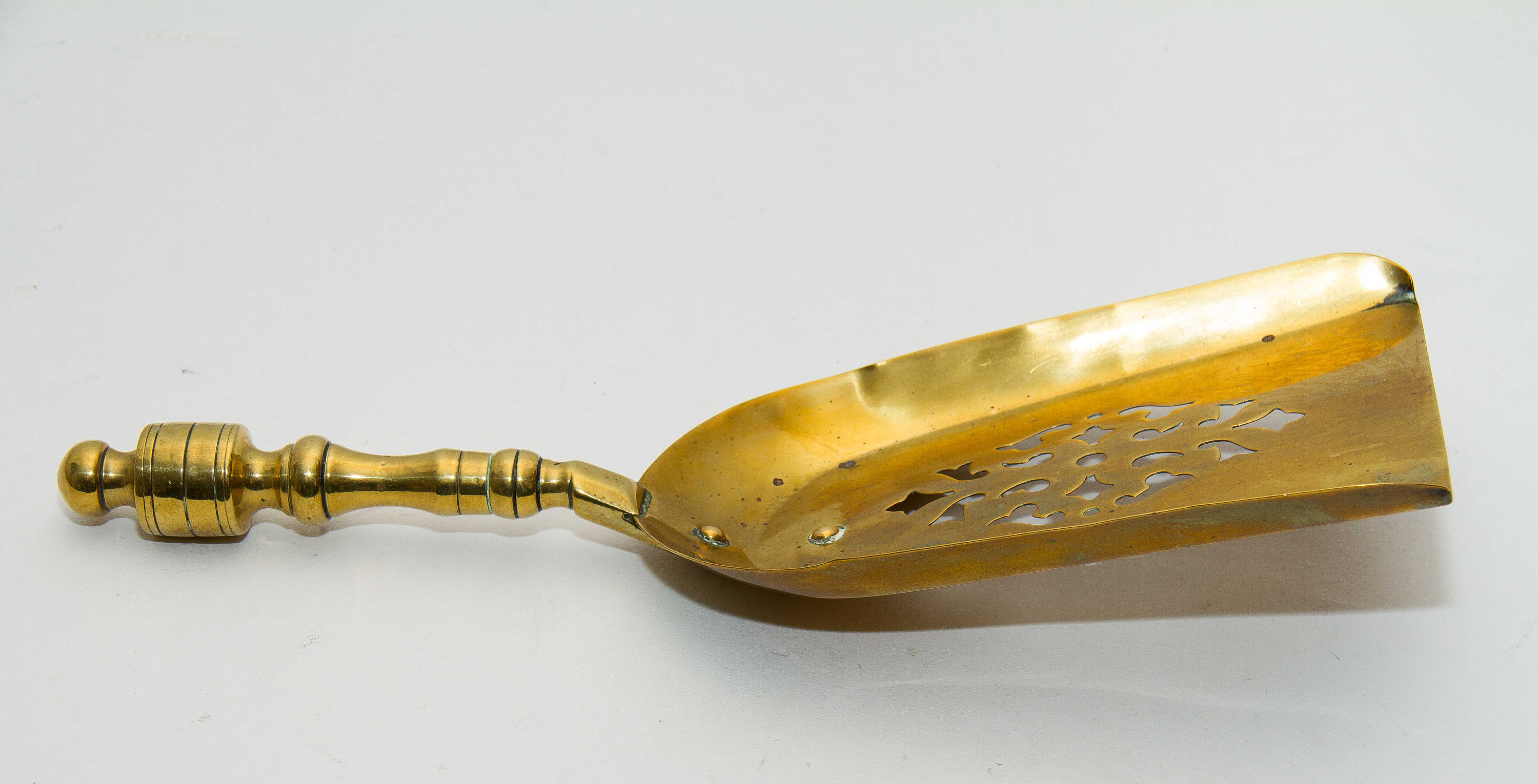 Brass decorative shovel cut out pattern fireside coal shovel fireplace accessory. Display prop bar cafe pub restaurant